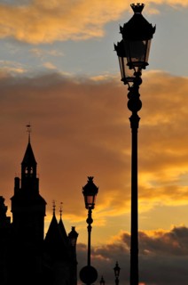 The Conciergerie and the typical Parisian street lights against dramatic clouds in the evening