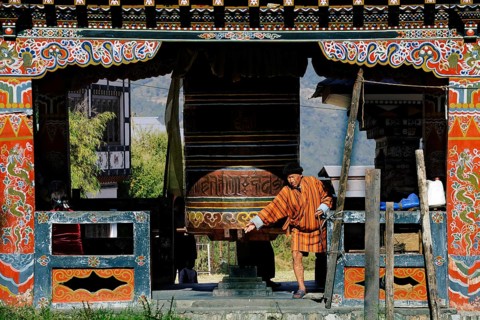 Man turning the large prayer wheel in the town centre of Mongar