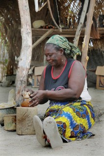 Elderly woman making pottery in front of her stall
