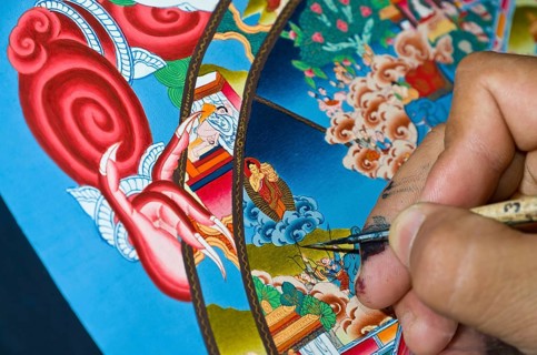 Artist painting a colourful Thangka in an art school