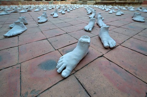 White sculptures of feet arranged as an art installation