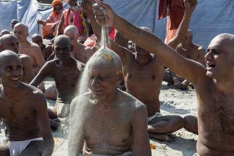 Man putting sand on the head of a another man joining the initiation of new sadhus