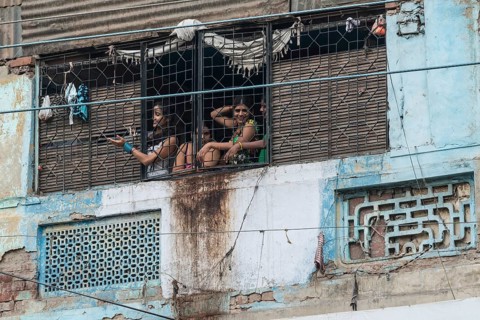 Prostitutes looking out of a window secured with bars waving to potential customers in the redlight district