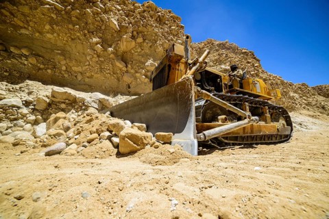 A caterpillar is cleaning the road after a landslide at a road construction site