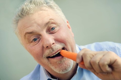 Senior eating a carrot with pleasure
