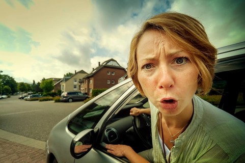 Angry woman car driver sticking out her head out of the window