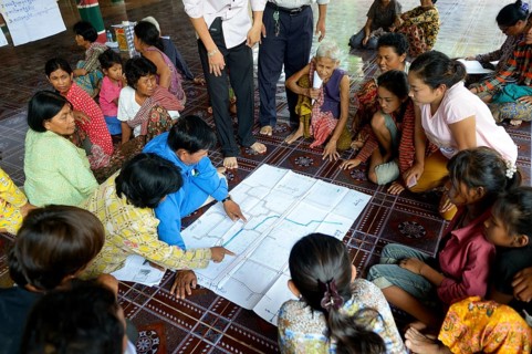 Men and women from the village discussing with representatives of a charity organization