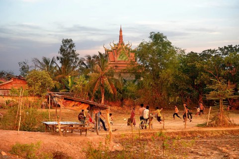 Boys playing football in front of a pagoda