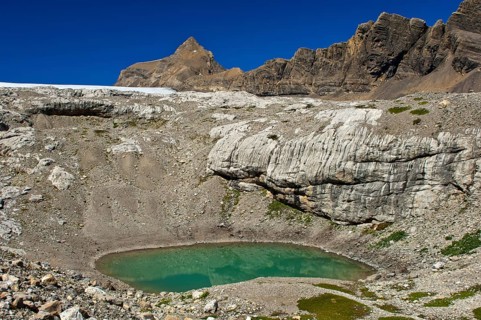Lake of green meltwater in a doline or sinkhole in the end moraine of Tsanfleuron Glacier at Sanetsch Pass