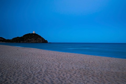 Baia di Chia beach with the Saracen Tower at dusk