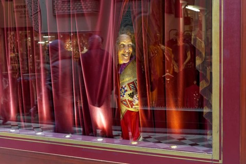 Wax figure looking through a gap in the curtain
