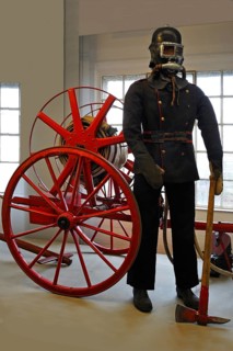 Firefighter wearing a breathing protection mask in front of a hose reel