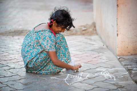 Girl creating a traditional Rangoli