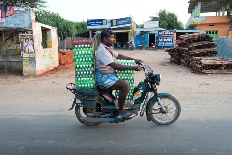 Man riding a scooter laden with eggs