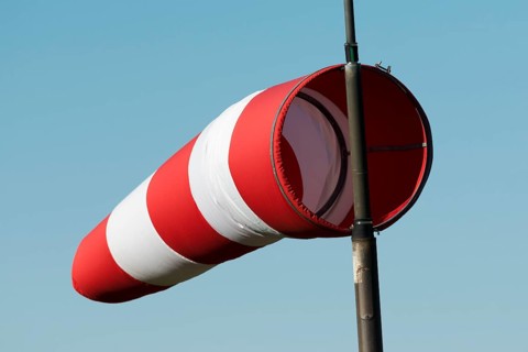Red and white windsock against a blue sky