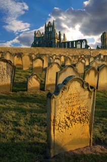 Whitby Abbey with grave stones in evening light