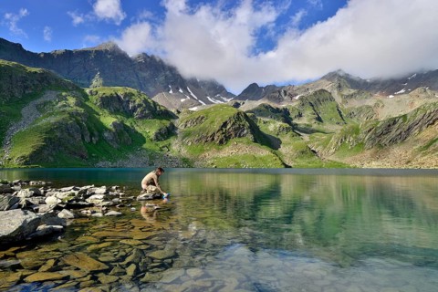 Mountaineer filling a water bottle at Grosser Schwarzsee Lake or Lago Nero