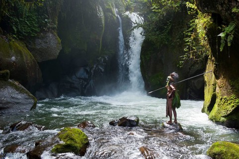 Decorated and painted tribal chief standing in front of a waterfall in the Highlands