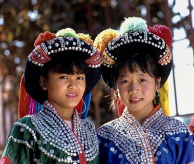 Two Lisu girls wearing colourful headdresses and the traditional costume of the mountain people