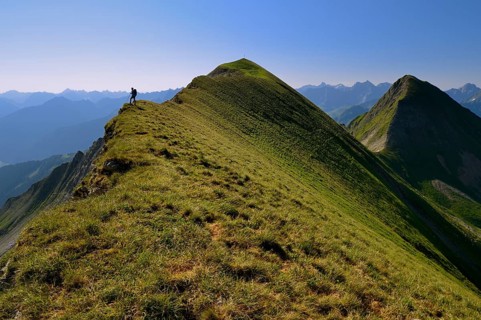 Mountaineer on the grassy summit ridge of Großer Krottenkopf Mountain