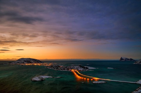 Fjord with an illuminated bridge in winter at sunset