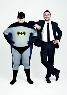 Athletic man wearing a suit beside a fat man dressed as a superhero