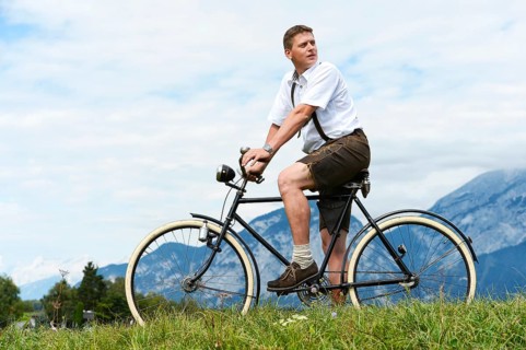 Man wearing leather pants on an old bicycle