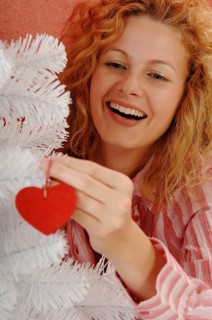 Woman is decorating a white Christmas tree