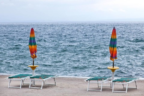 Umbrellas and deckchairs during the preseason on the beach of Opatija on the Mediterranean Sea in Kvarner Bay