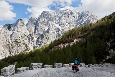 Cyclist in the mountain landscape near the Vrsic Pass with the 2547m high Prisojnik Mountain