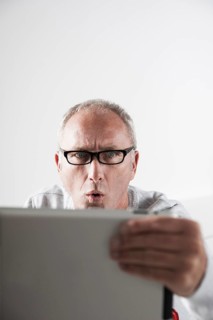 Man looking at a tablet PC with a stunned expression