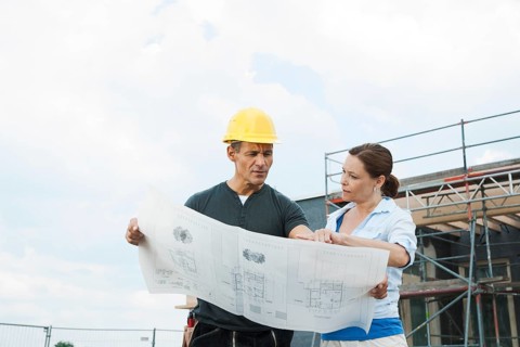 Construction manager and building owner discussing plans on a construction site
