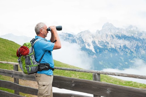 Hiker looking at the Tannheim mountains with binoculars