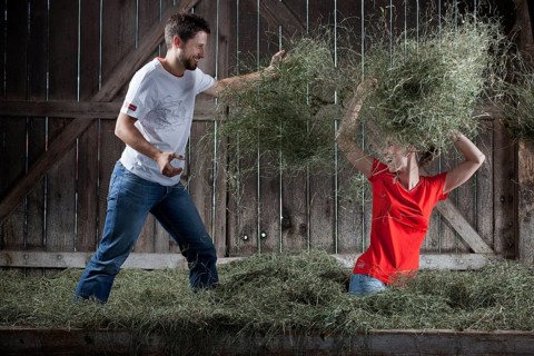 Young couple throwing hay at each other on a farm