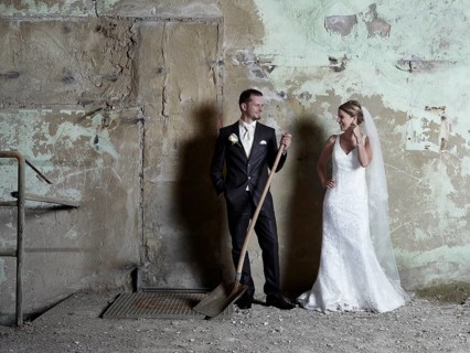 Bridal couple standing in front of a wall in an old industrial hall