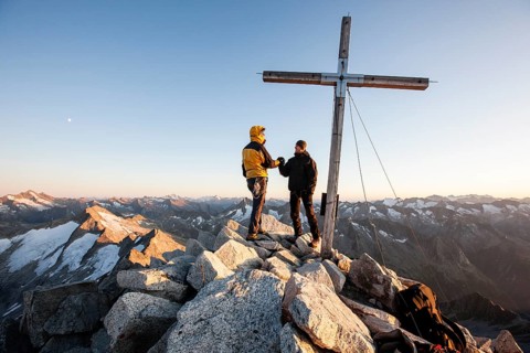 Mountain climbers on the summit cross of Reichenspitze Mountain