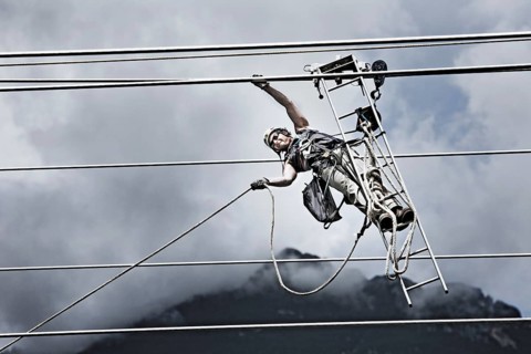 High-voltage service technician pulling a rope to get to the next pylon