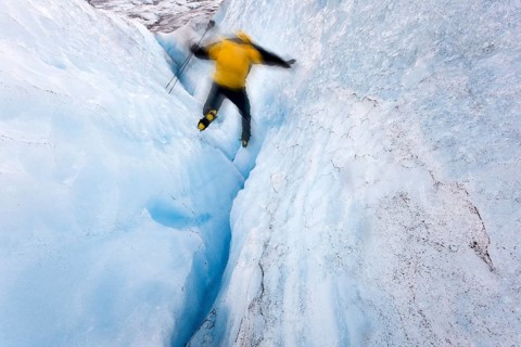 Mountaineer jumping into a small crevasse on Matanuska Glacier