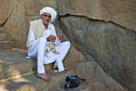 A pilgrim dressed in white is sitting on the stairs leading up to the temple on the holy mountain of Girnar