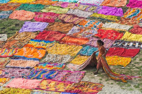 Colourful saris laying to dry after washing on a sandbank on the banks of the Yamuna River
