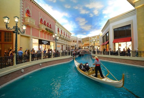 Gondolier in a Gondola with tourists in a replica of Venetian streets under an artificial sky