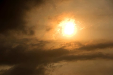 Sun behind clouds and brownish ash and gas clouds of the Holuhraun fissure eruption