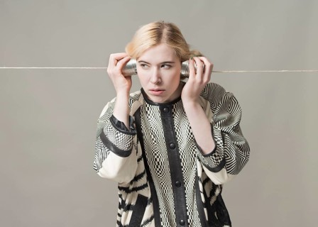 Blond woman listening with tin can phone