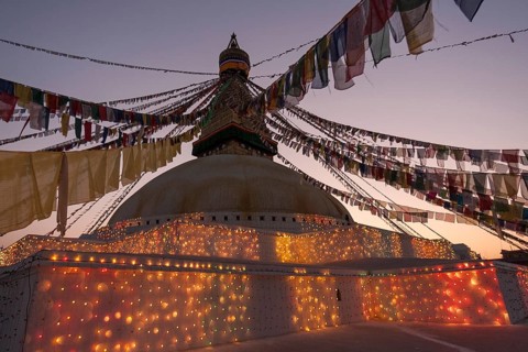 Boudhanath Stupa decorated with prayer flags and lights for the full moon festival