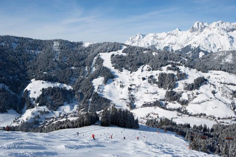 Skiers on slope in front of mountains