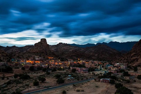 Small village of Aguard Oudad with brightly painted houses in front of the rock Chapeau Napoleon