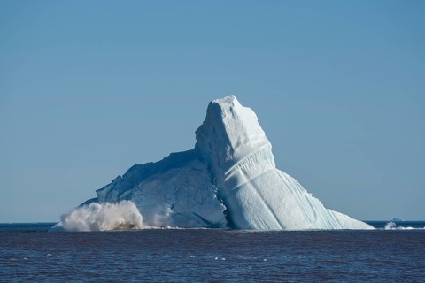 Pieces breaking off an enormous iceberg causing it to unbalance and collapse