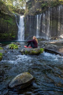 Young woman sitting on a stone in a river