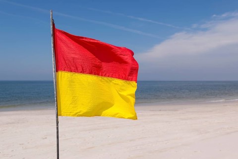 A red-yellow flag waves on the beach