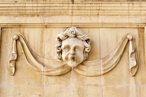Baroque-style face on a fountain at St. John's Co-Cathedral